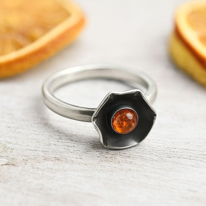 Silberring mit oxidiertem Blütenkopf und orange leuchtendem Bernstein