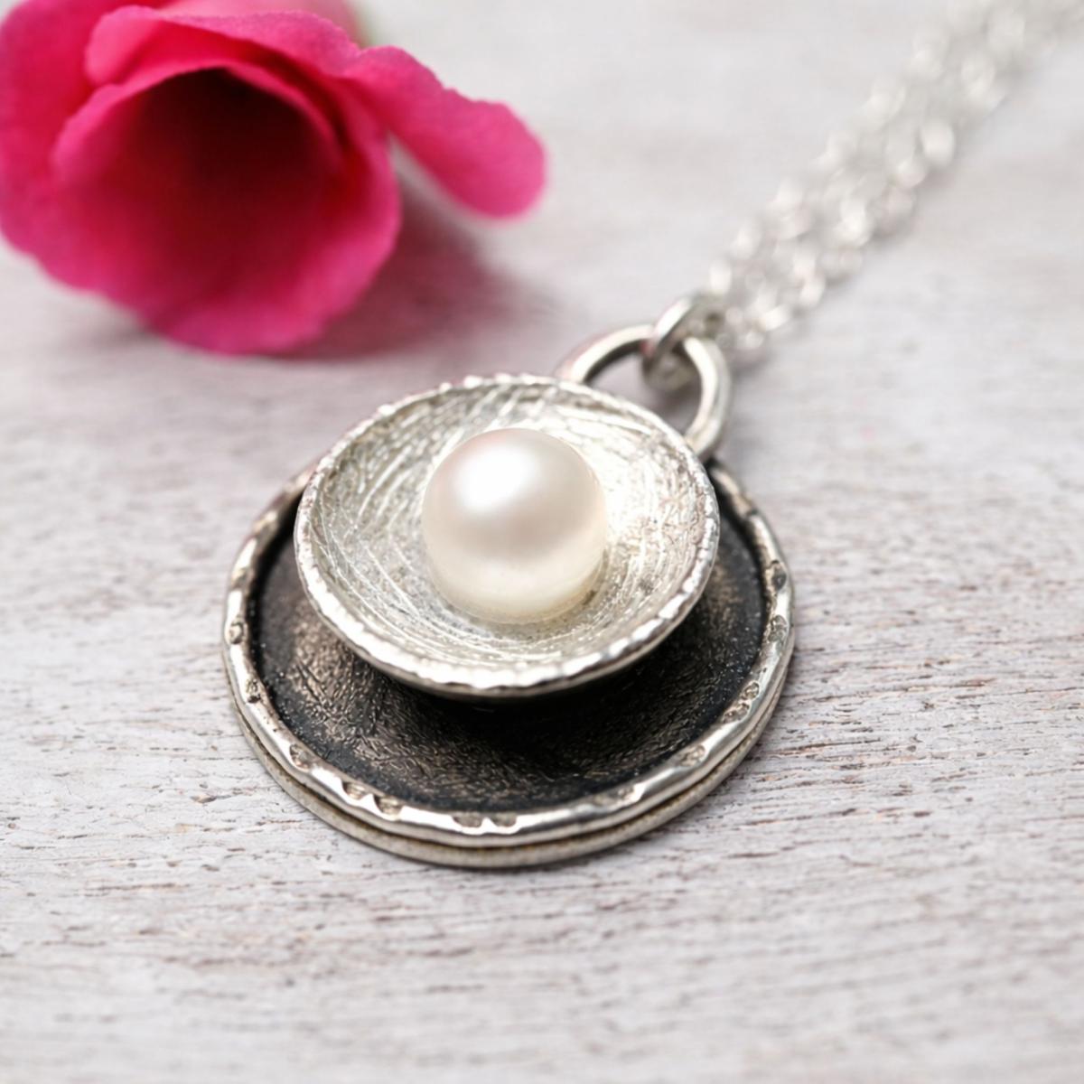 Handgemachter runder Anhänger mit schmückender Perle und toller Kratzstruktur auf der Oberfläche.